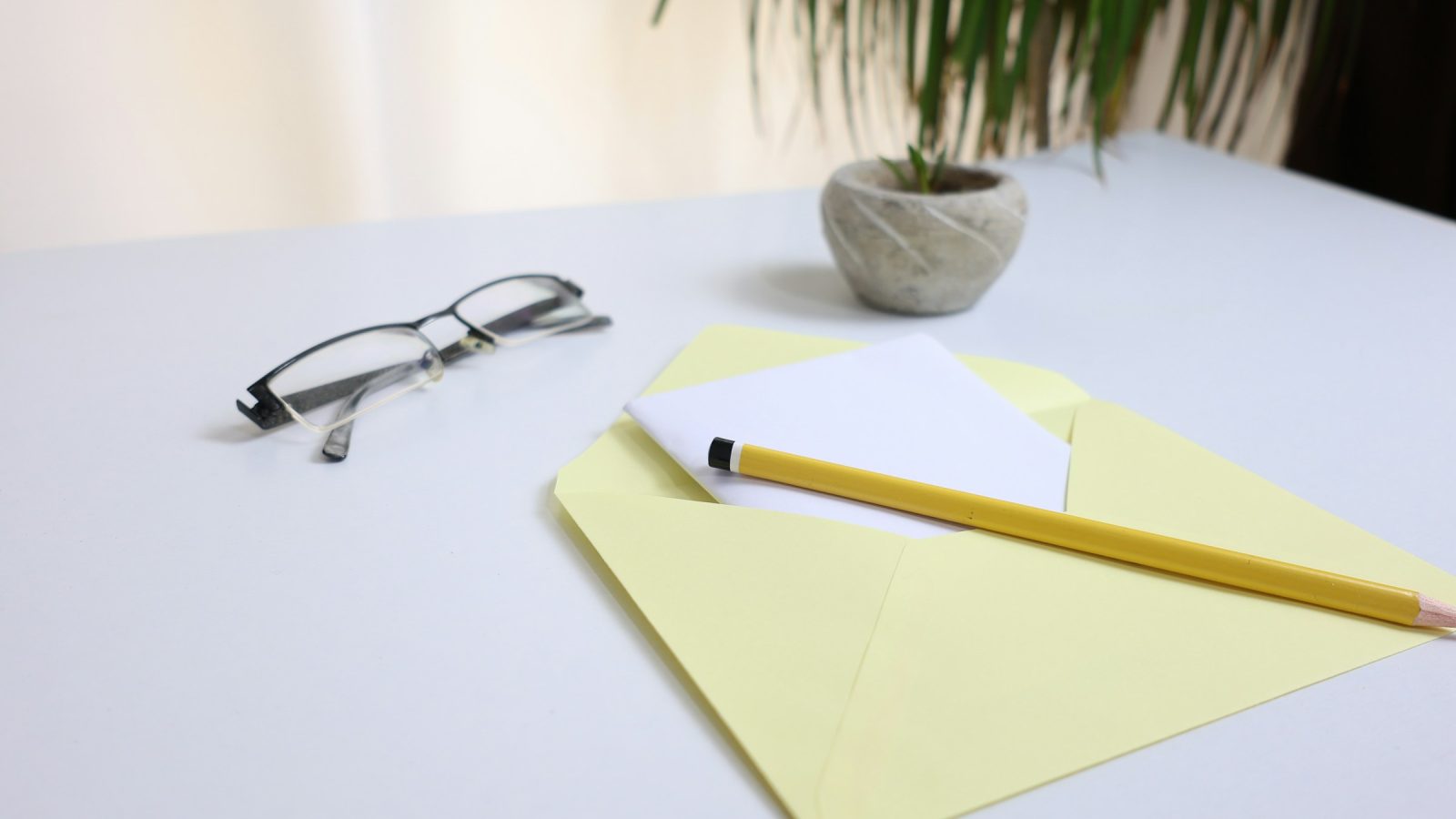 Glasses and a pencil beside an open envelope on a desk