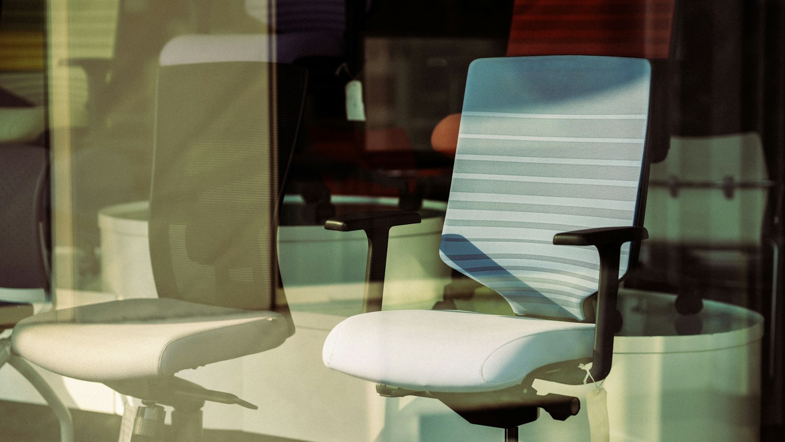 An empty white office chair seen through a glass window